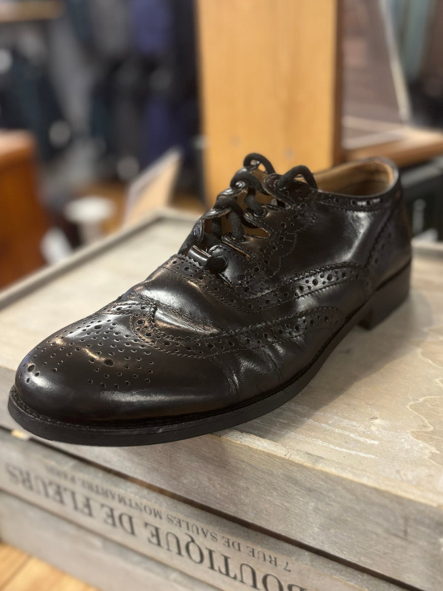Black leather shoe on a wooden box with a clothing store background