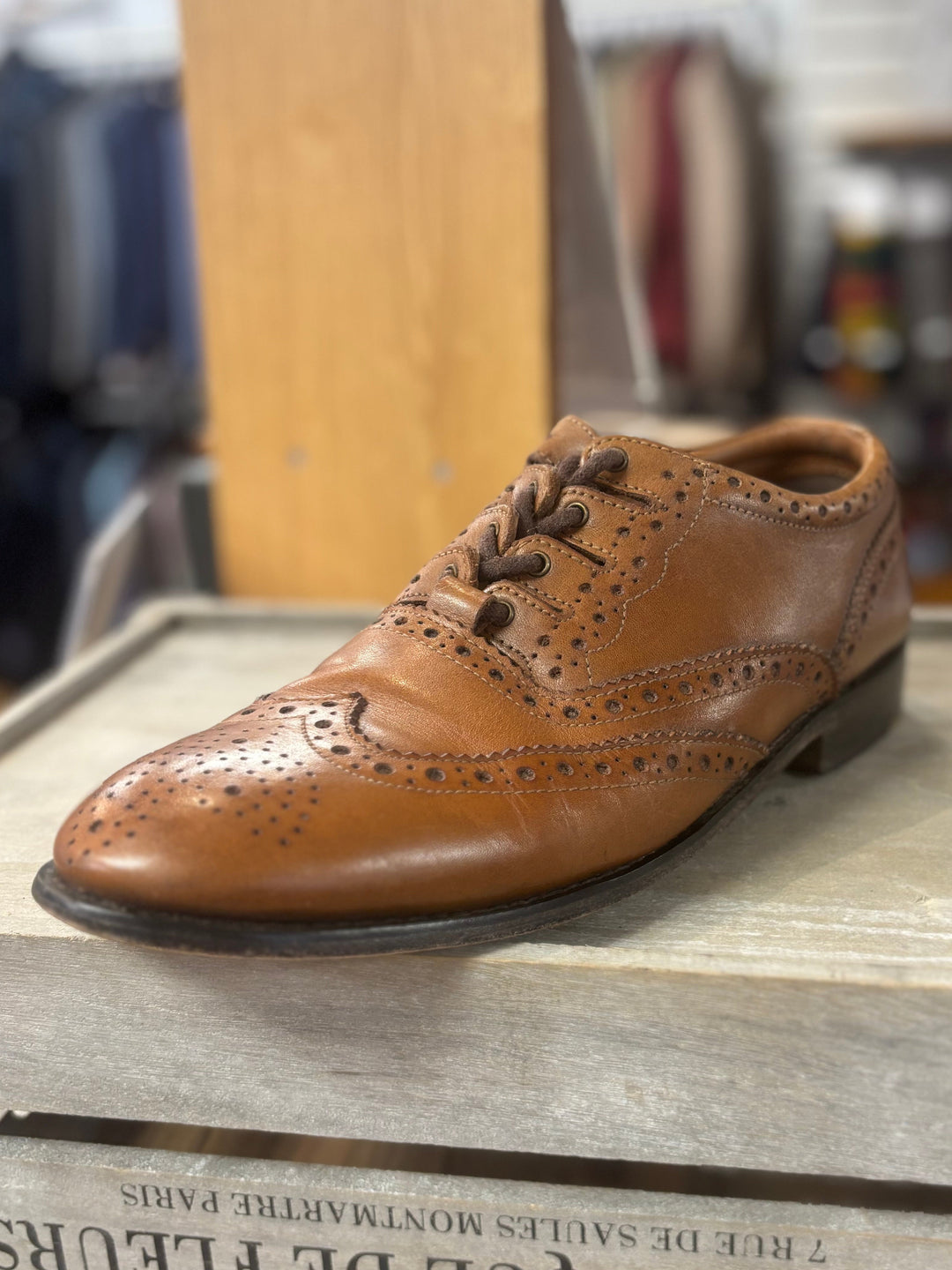 Brown leather shoe on a wooden box with a blurred background