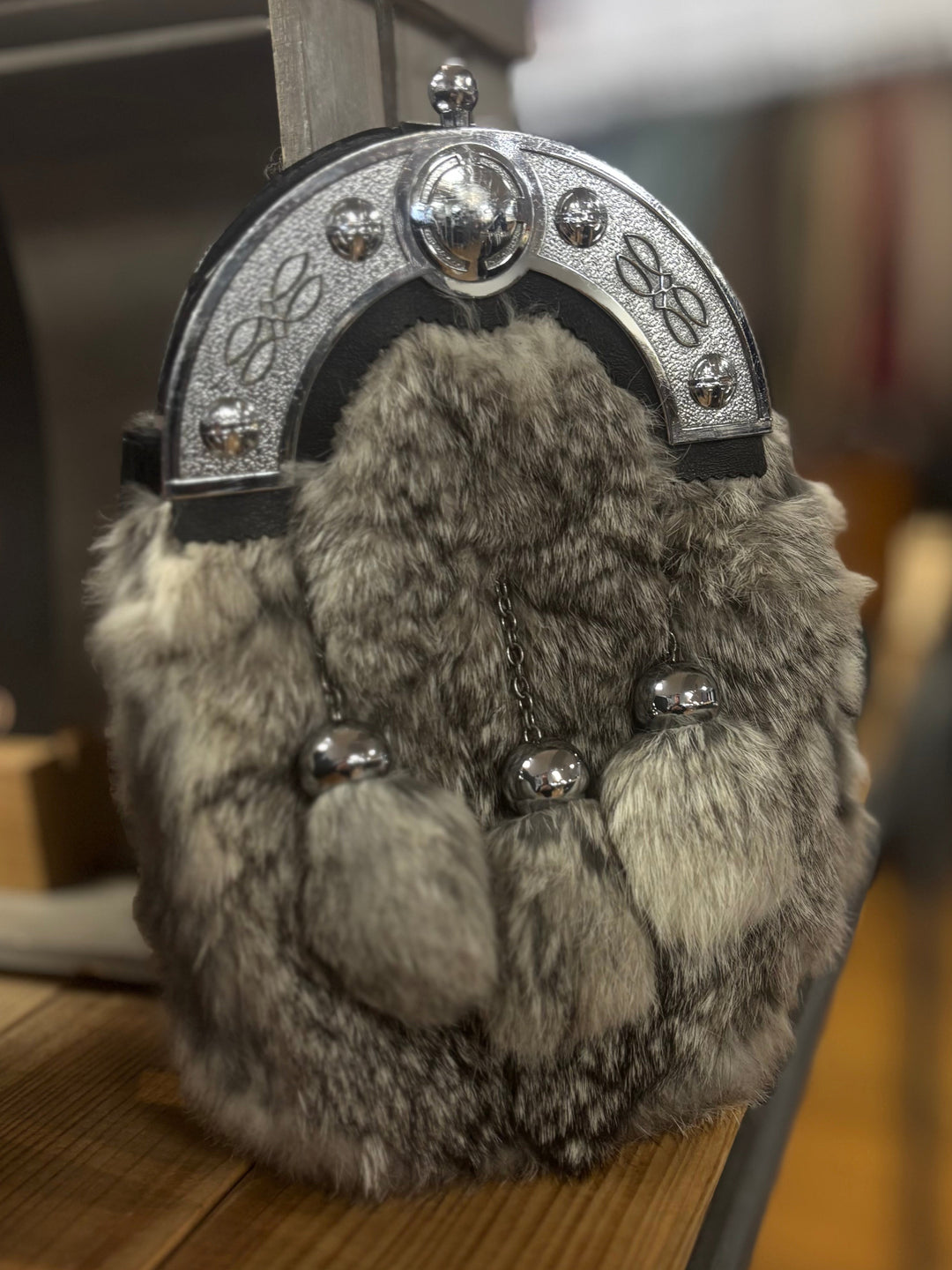 Decorative keychain with fur-like texture and metallic accents on a wooden surface.
