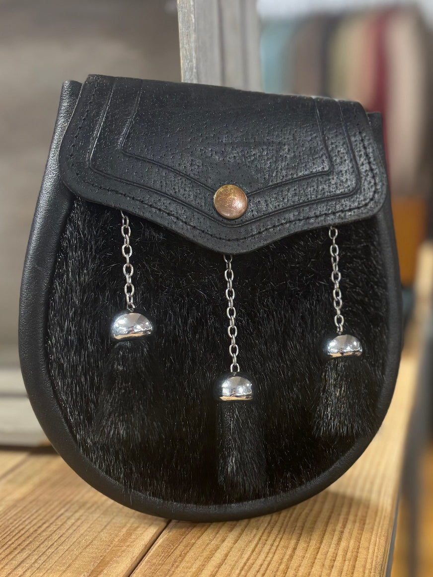 Black leather pouch with decorative elements on a wooden surface