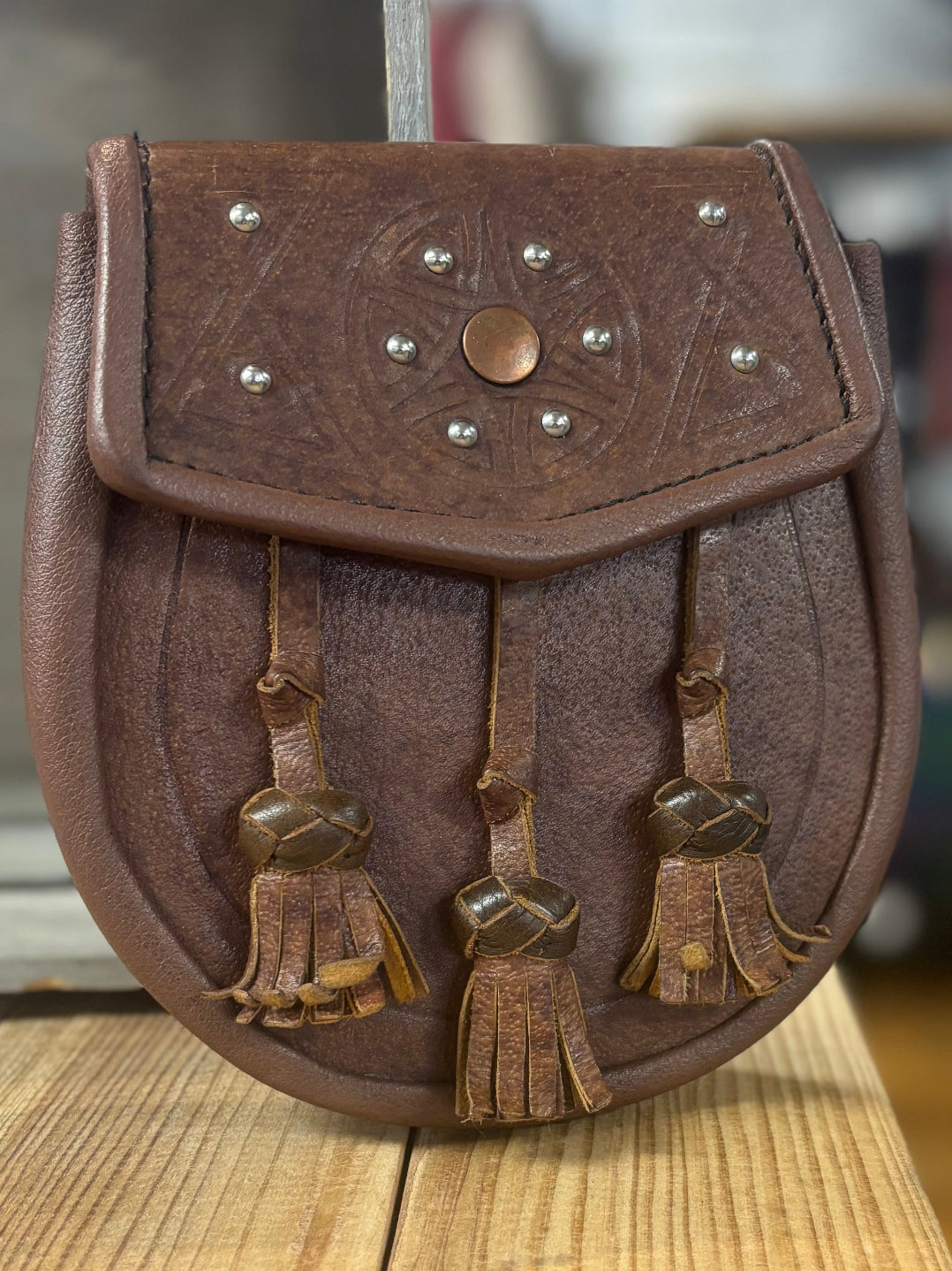 Brown leather pouch with tassels on a wooden surface